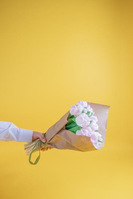 A vibrant display of floral arrangements featuring bright yellow sunflowers with large, sunny petals and dark centers, accompanied by smaller, pale yellow daisies with dark centers, all wrapped in bro