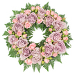 Captured from a top-down angle on a bright white background, this memorial wreath forms a complete, unbroken circle of roses and greenery, symbolising continuity and everlasting remembrance. The arrangement is dominated by generous, fully open roses in a mellow palette of dusty lavender, antique mauve, and greyish-purple, each bloom showing layers of softly folded petals that create lush, rounded rosettes. These larger roses are carefully spaced so that their tones repeat evenly around the wreath, establishing a calm, rhythmic pattern. Between them, smaller blush-pink spray roses appear in clusters, with buds and partially opened flowers mingling to lend a sense of gentle progression and life. The base of the wreath is composed of dense, dark green fern fronds, their fine, serrated leaflets spreading outward like feathers to form a deep, textural cushion beneath the blossoms. Occasional touches of darker filler greens and tiny buds peek through the petals, adding shadow and depth, as though the flowers were emerging from a shaded garden corner near the streets of Upper Clapton. The lighting is soft and neutral, ensuring that the colours remain subtle and the textures of both petals and foliage are easily distinguished without glare. The mood is contemplative and respectful, suggesting a tribute that might be sent to a funeral or memorial service in the local area, perhaps placed near a photograph or candle display. It reflects the care of a neighbourhood florist familiar with creating funeral wreaths that offer comfort, quiet beauty, and a dignified way to honour a loved one's memory within the Upper Clapton community.