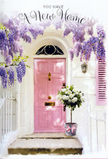 This photograph evokes the feeling of discovering a hidden, flower-draped entrance just off the busier stretches of Upper Clapton, perhaps a few steps from Clapton Common where the trees open to sky. A blush-pink door is the gentle focal point, its paint finish smooth and matte, offering a soft contrast to the clean white walls and a matching pastel shutter. The simplicity of the architecture is transformed by the abundance of wisteria falling from above. Long strands of lilac and lavender blooms cascade down like a fragrant veil, the tiny clustered petals combining into lush clouds that sway slightly in the breeze you can almost feel. The wisteria partially frames the door and filters the light, casting delicate shadows that ripple across the threshold. At the base of the door sits a grey metal bucket, pressed into service as a charming, slightly rustic vase. It is overflowing with creamy white roses-generous, many-petalled, and velvety to the eye-layered together so that they create a cushion of soft, rounded forms. Threads of fresh green foliage slip between the roses, offering little flashes of colour that break up the expanse of cream. Around the bucket, a pink ribbon is tied in an understated bow, its colour harmonising with the front door and helping to pull the whole composition together. The scene feels like a quiet but heartfelt celebration, perfect for flowers sent to mark a new chapter in a Hackney life-a move into an Upper Clapton flat, perhaps, or simply the desire to make a familiar doorway feel newly cherished and endlessly welcoming.